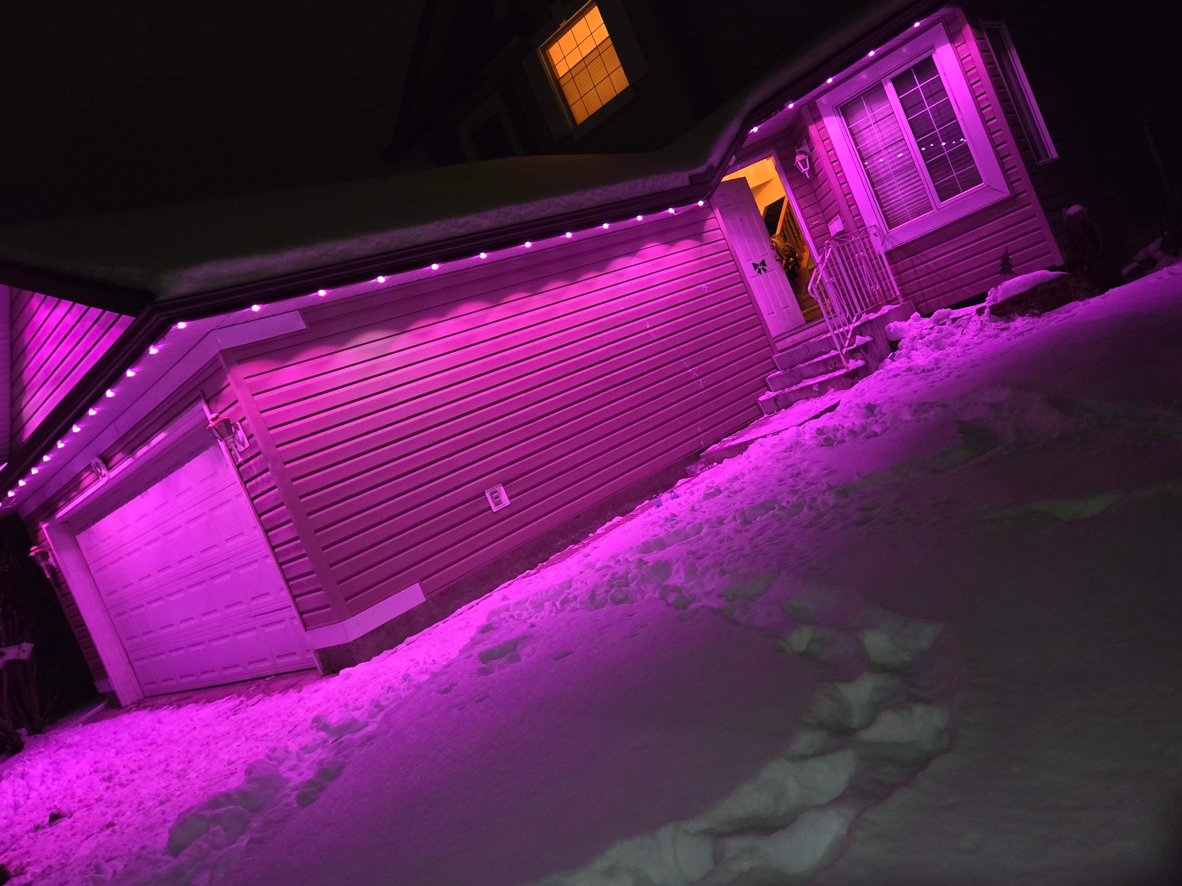 Bungalow washed in vivid magenta permanent lights over deep winter snow