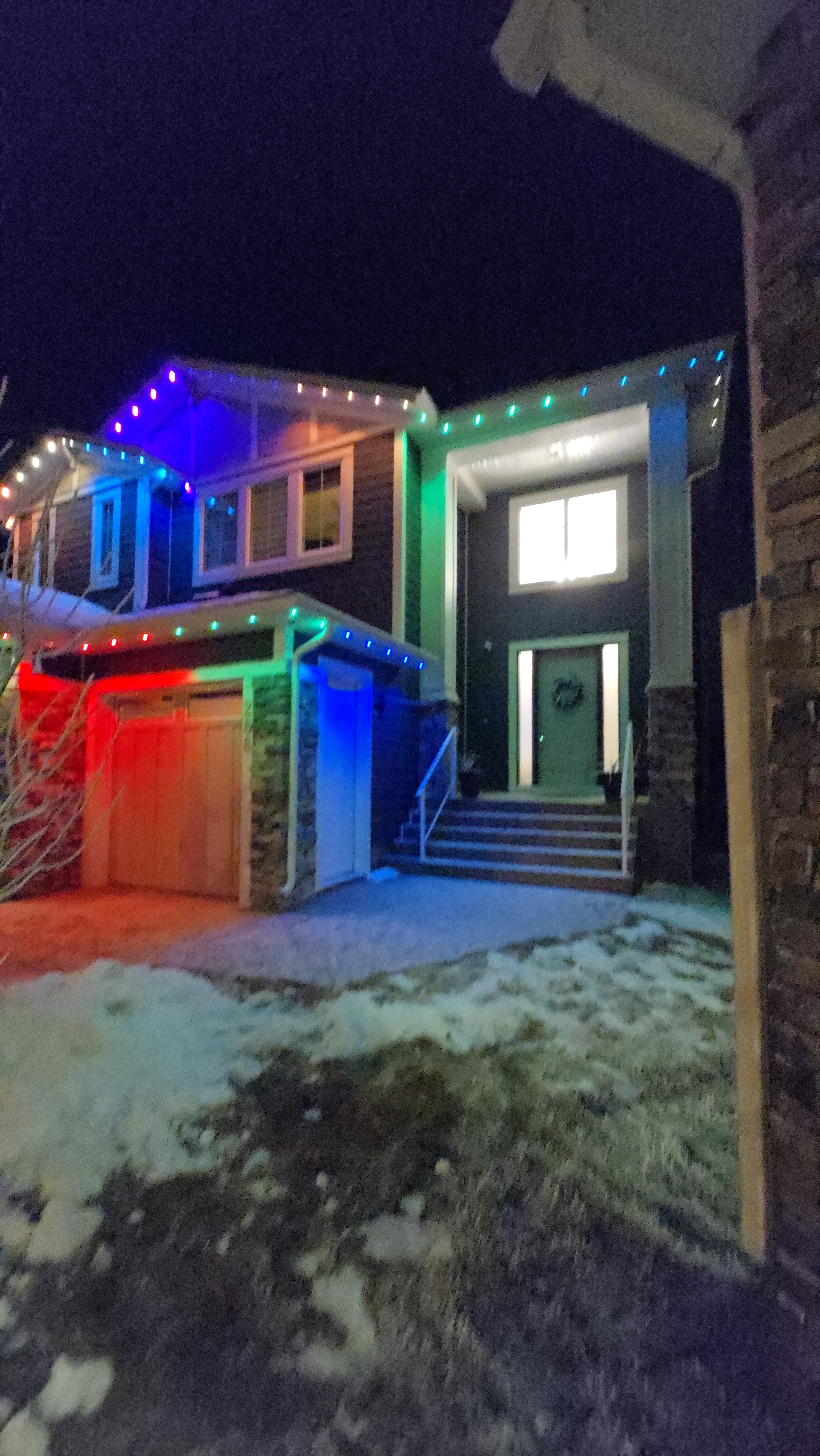 Home lit in a bold blue, green and red multicolour pattern across the eaves