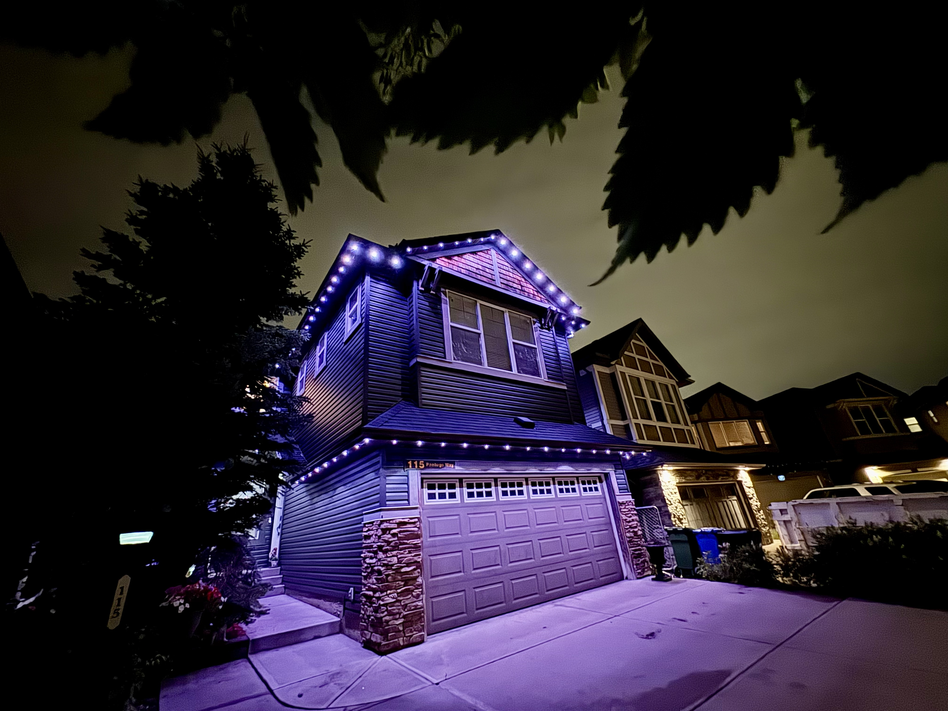 Dramatic wide-angle of a home glowing white and purple at night
